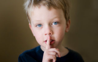 A child signaling silence with a finger on his mouth