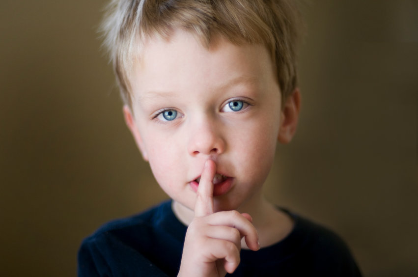 A child signaling silence with a finger on his mouth