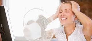 A woman using an electric fan to cool herself