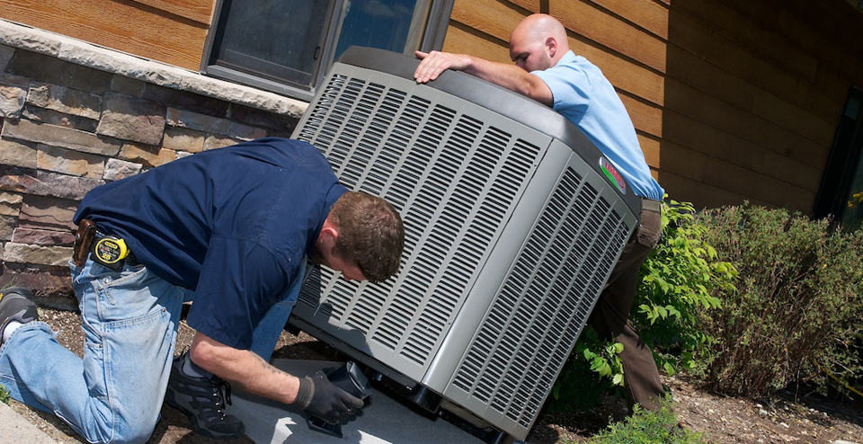 Two HVAC contractors installing an AC unit