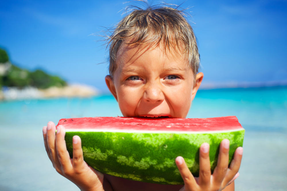 Little boy on Miami Beach eating a slice of watermelon.