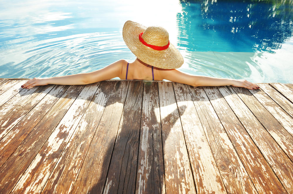 image of woman wearing a hat cooling off in Miami pool.