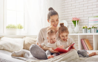 Image of a mother sitting in well air conditioned room reading to her two young children.