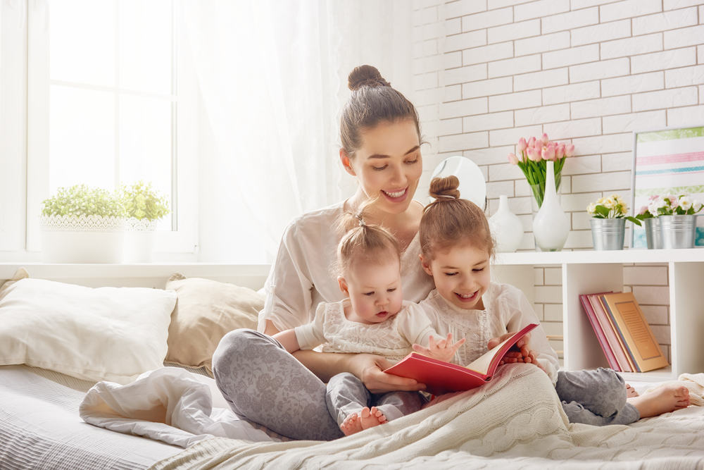 Image of a mother sitting in well air conditioned room reading to her two young children.