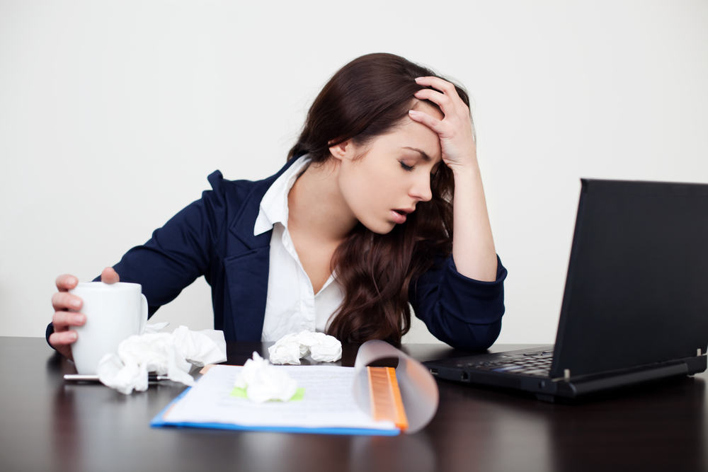 Image of young female office worker sick at her desk.