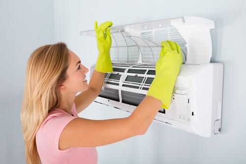 Image of woman with broken AC trying to fix it.