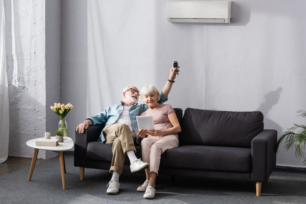 Old Couple sitting on a sofa under air conditioner