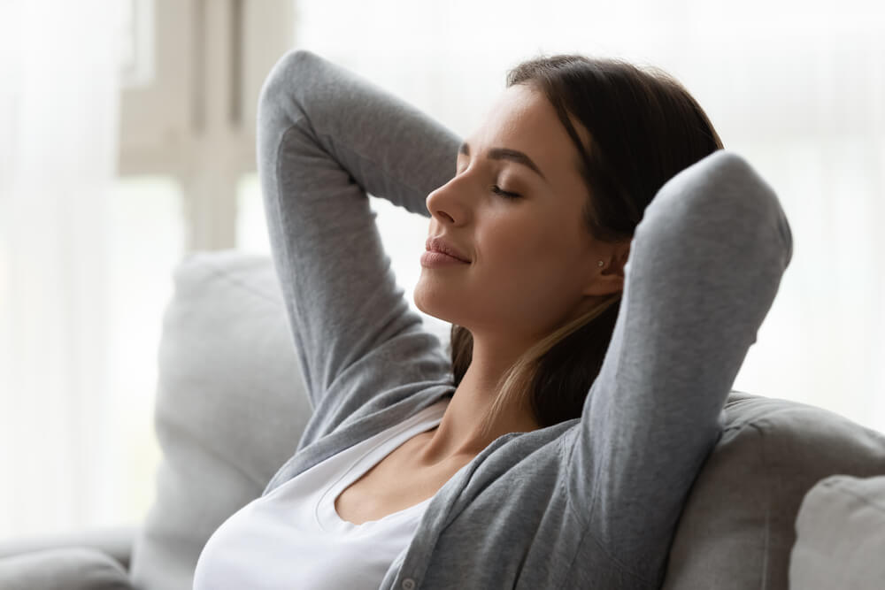 Close Up of Dreamy Millennial 20S Woman Closed Eyes Putting Hands Behind Head Enjoy Relaxation, Do Meditation Resting on Weekend Relish Lazy Day at Home.