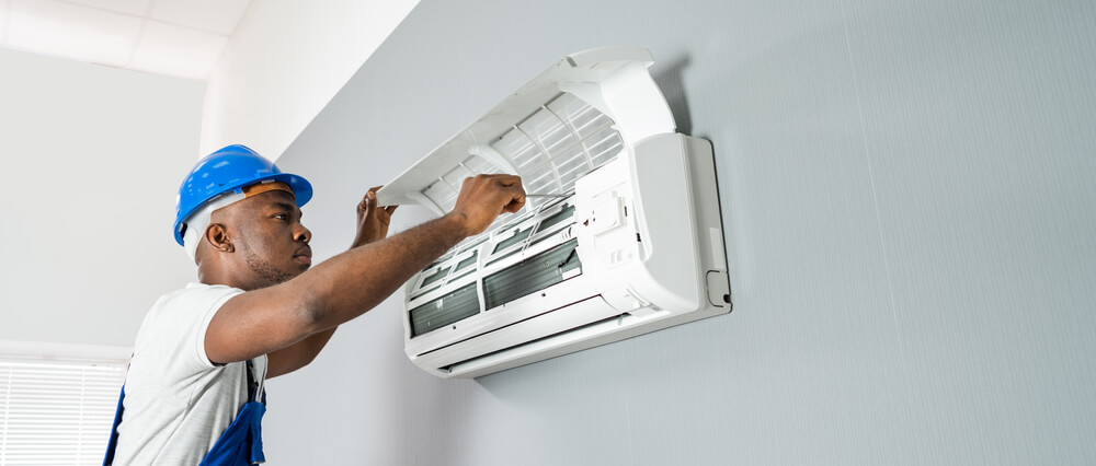 Happy Young African Male Technician Repairing Air Conditioner