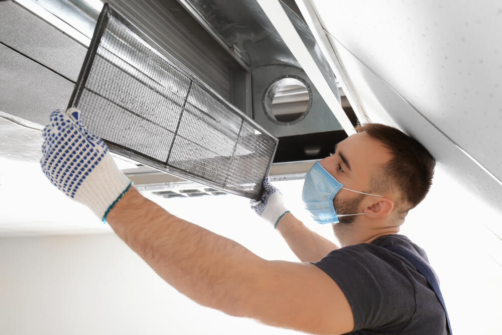Male Technician Cleaning Industrial Air Conditioner Indoors