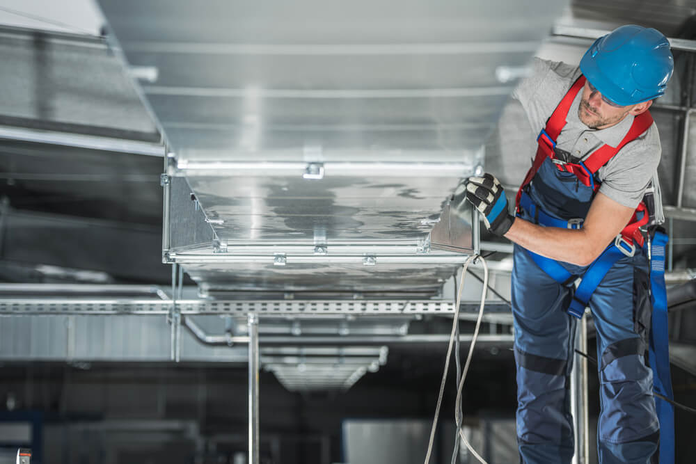 Warehouse heating and cooling system installation by professional caucasian technician.