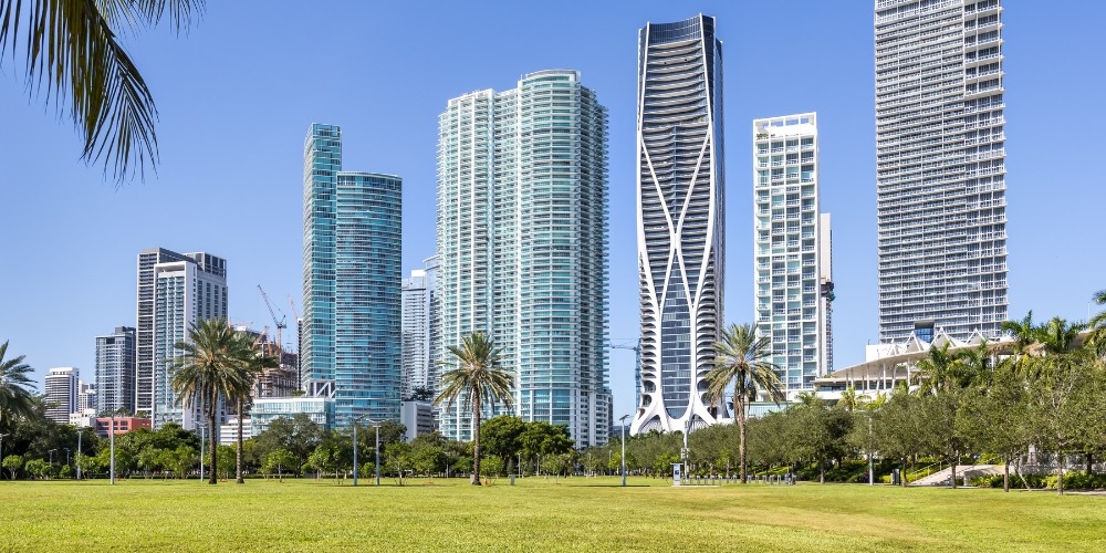 Lush green grass in the foreground with tall urban buildings visible in the distance | Chills AC