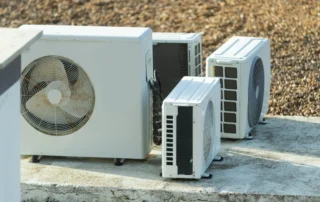 Group of outdoor air conditioning condenser units on a concrete pad in an outdoor setting.